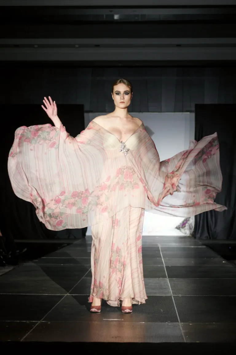 Beautiful fashion model at runway in flying silk dress