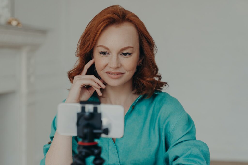 Photo of positive redhead woman blogger influencer shoots video for personal blog