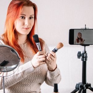 Beauty blogger influencer leads online stream. Young woman shows how to do makeup and use cosmetics.